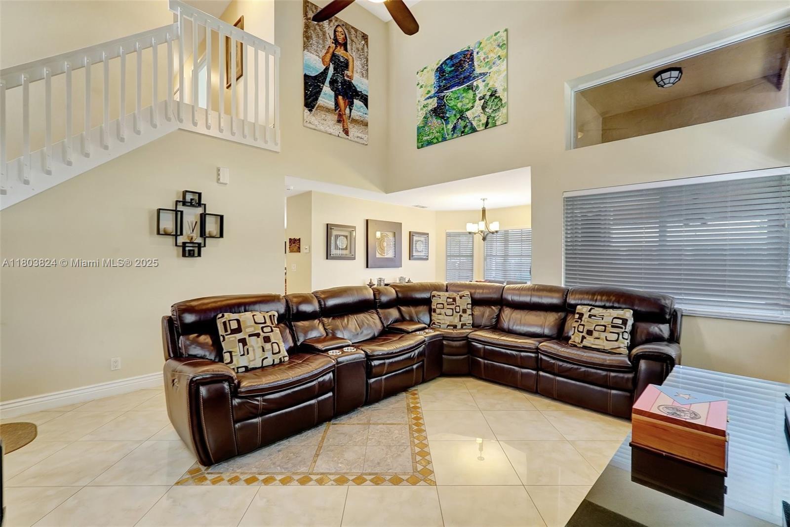 10920 SW 11th Ct, Davie, FL 33324 - living area with light tile patterned floors, a chandelier, a ceiling fan, a towering ceiling, and stairs