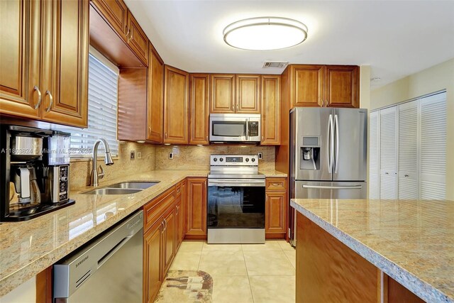 10920 SW 11th Ct, Davie, FL 33324 - kitchen featuring stainless steel appliances, a sink, backsplash, light tile patterned flooring, and brown cabinets