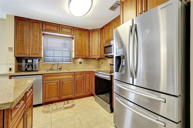 10920 SW 11th Ct, Davie, FL 33324 - kitchen featuring appliances with stainless steel finishes, a sink, tasteful backsplash, brown cabinetry, and light stone counters