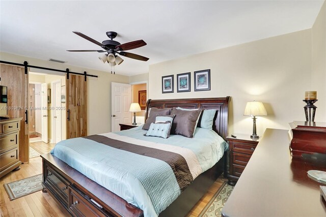 10920 SW 11th Ct, Davie, FL 33324 - bedroom featuring a barn door, light wood finished floors, ceiling fan, and connected bathroom