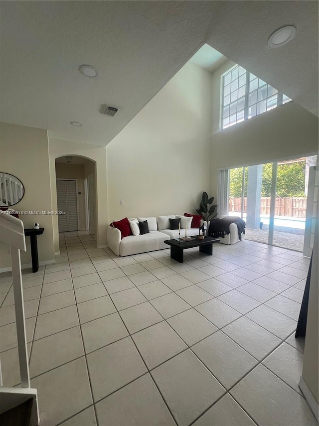 9942 SW 158th Ct, Miami, FL 33196 - living area featuring light tile patterned flooring, arched walkways, a high ceiling, and baseboards
