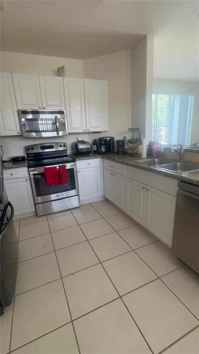 9942 SW 158th Ct, Miami, FL 33196 - kitchen with stainless steel appliances, a sink, white cabinets, light tile patterned floors, and dark countertops