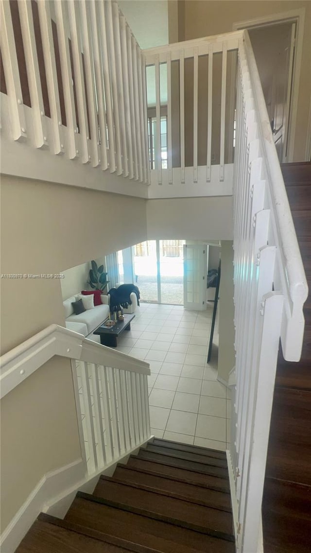 9942 SW 158th Ct, Miami, FL 33196 - staircase featuring tile patterned floors, a towering ceiling, and baseboards