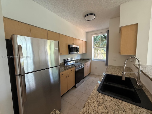 616 Clearwater Park Rd Unit 212, West Palm Beach, FL 33401 - kitchen featuring stainless steel appliances, a sink, a textured ceiling, light tile patterned flooring, and light brown cabinetry