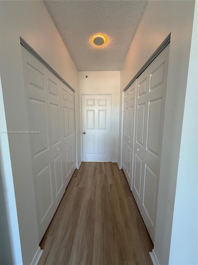 616 Clearwater Park Rd Unit 212, West Palm Beach, FL 33401 - hallway with a textured ceiling, wood finished floors, and baseboards