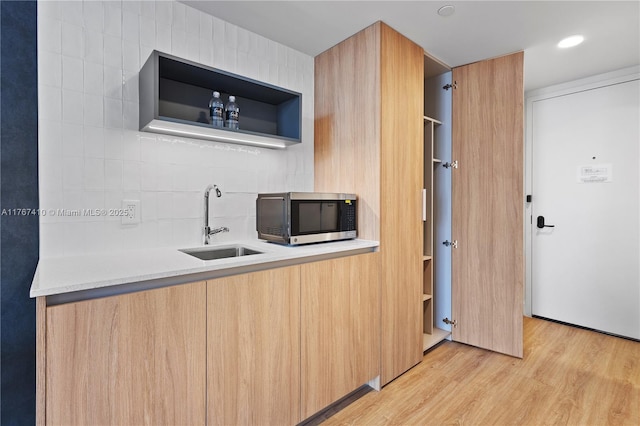 601 NE 1st Ave Unit 2004, Miami, FL 33132 - kitchen featuring stainless steel microwave, a sink, modern cabinets, light wood-style floors, and tasteful backsplash