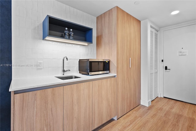 601 NE 1st Ave Unit 2004, Miami, FL 33132 - kitchen with stainless steel microwave, a sink, light wood finished floors, tasteful backsplash, and light countertops