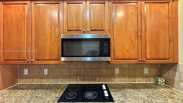 8716 Blaze Ct, Davie, FL 33328 - kitchen view of stainless steel microwave, black electric stovetop, backsplash, and brown cabinets