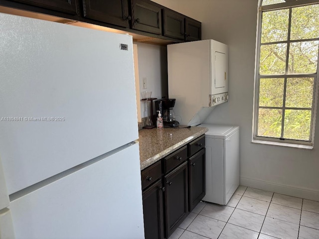 kitchen with freestanding refrigerator, baseboards, and light stone counters