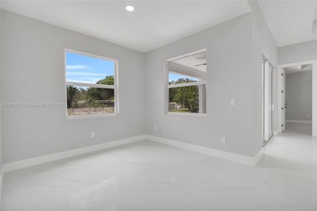 418 8th Ave, Lehigh Acres, FL 33972 - empty room featuring baseboards, healthy amount of natural light, marble look tile flooring, and recessed lighting