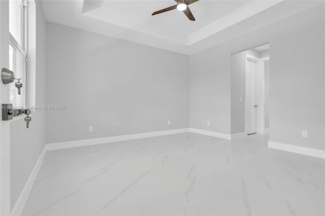 418 8th Ave, Lehigh Acres, FL 33972 - unfurnished room featuring marble look tile flooring, a ceiling fan, a raised ceiling, and baseboards