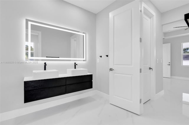 418 8th Ave, Lehigh Acres, FL 33972 - bathroom featuring marble look tiles, double vanity, and baseboards
