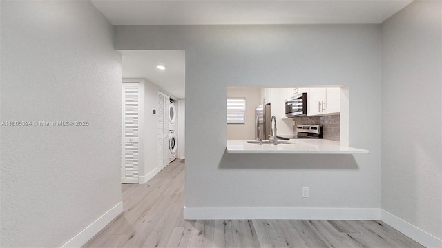15805 W Waterside Cir Unit 202, Sunrise, FL 33326 - kitchen with appliances with stainless steel finishes, estacked washer and dryer, light countertops, white cabinets, and light wood-type flooring
