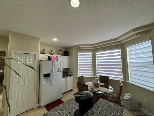 4892 NW 109th Pl, Doral, FL 33178 - kitchen featuring white fridge with ice dispenser, light tile patterned floors, white cabinets, a textured ceiling, and recessed lighting