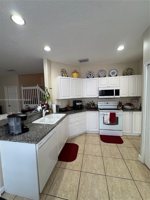 4892 NW 109th Pl, Doral, FL 33178 - kitchen with white appliances, a sink, white cabinetry, light tile patterned floors, and a peninsula
