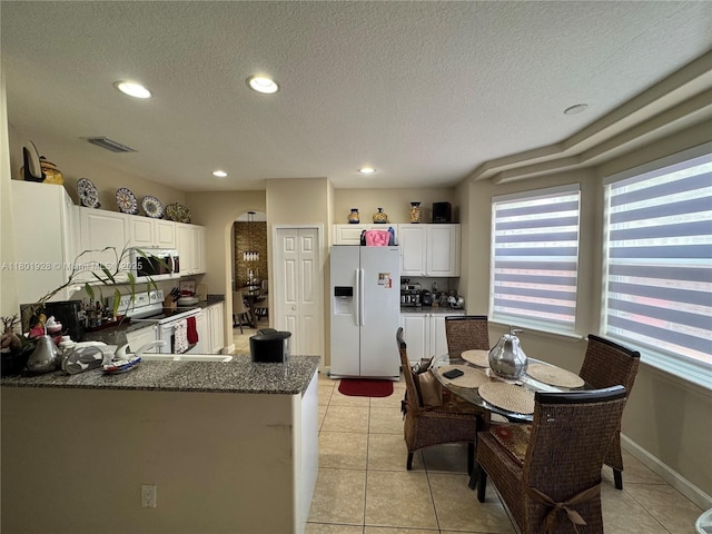 4892 NW 109th Pl, Doral, FL 33178 - kitchen featuring white appliances, arched walkways, a textured ceiling, recessed lighting, and light tile patterned floors
