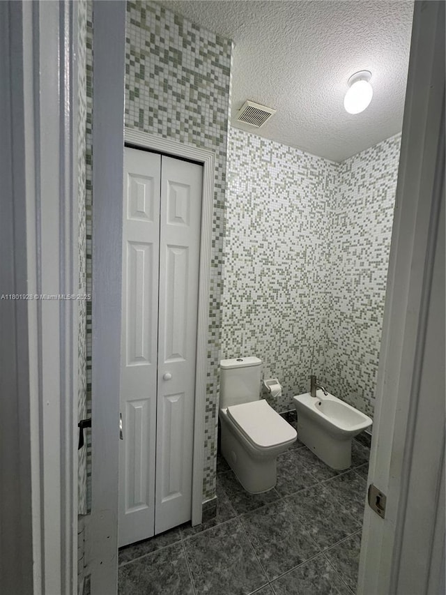 4892 NW 109th Pl, Doral, FL 33178 - bathroom with a closet, toilet, a textured ceiling, a bidet, and tile patterned floors