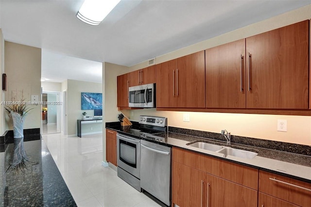 3001 S Ocean Dr Unit 321, Hollywood, FL 33019 - kitchen with appliances with stainless steel finishes, a sink, light tile patterned floors, dark stone counters, and brown cabinets