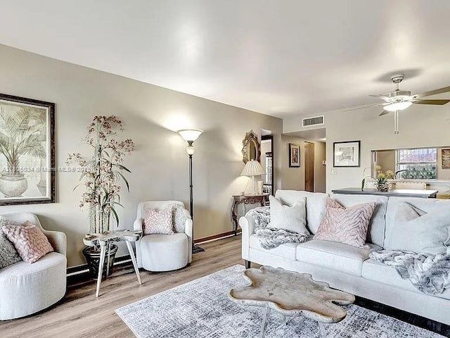 living area with light wood-style flooring, a ceiling fan, and baseboards