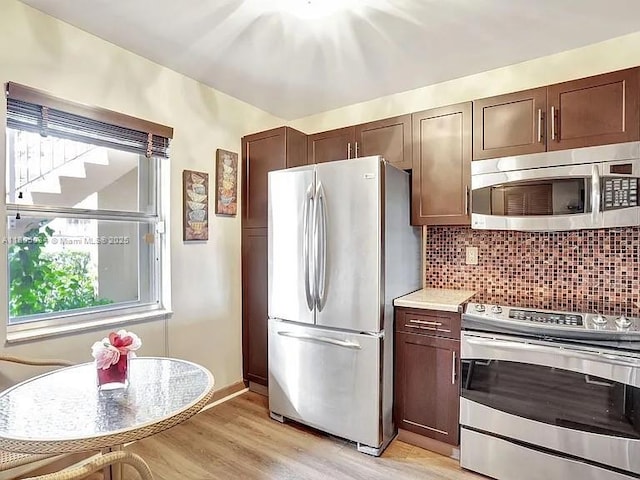 kitchen featuring stainless steel appliances, light wood finished floors, tasteful backsplash, light countertops, and dark brown cabinets