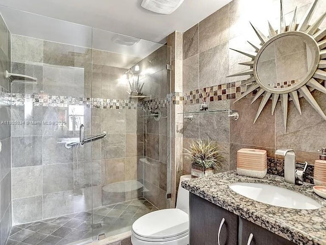 bathroom with toilet, a shower stall, tile walls, and vanity