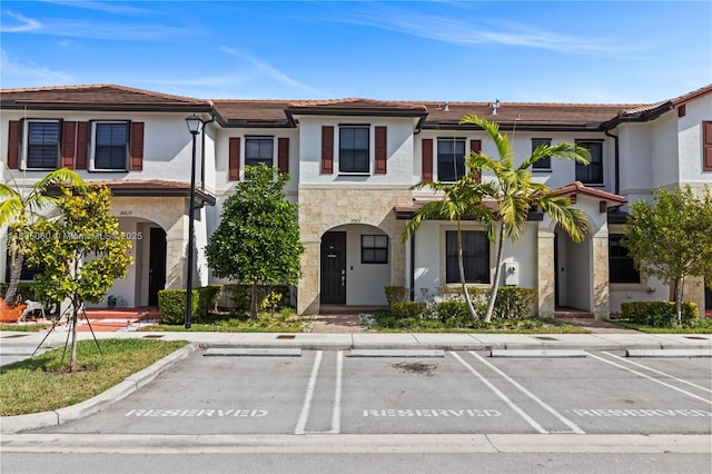 10611 W 33rd Ct, Hialeah, FL 33018 - view of property featuring uncovered parking, stucco siding, a tiled roof, and stone siding
