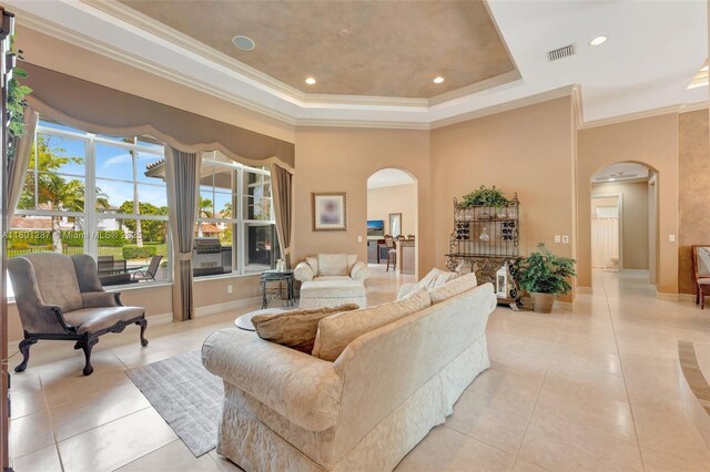 12668 NW 74th Pl, Parkland, FL 33076 - living area featuring arched walkways, light tile patterned flooring, ornamental molding, a tray ceiling, and baseboards