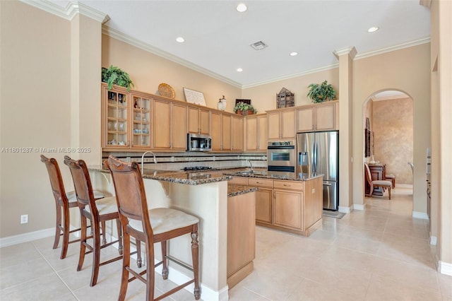 12668 NW 74th Pl, Parkland, FL 33076 - kitchen with appliances with stainless steel finishes, arched walkways, a peninsula, dark stone countertops, and a kitchen bar