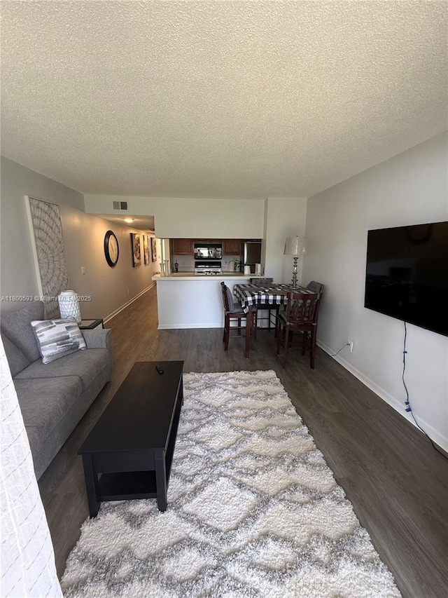 living room featuring a textured ceiling, dark wood-style floors, and baseboards