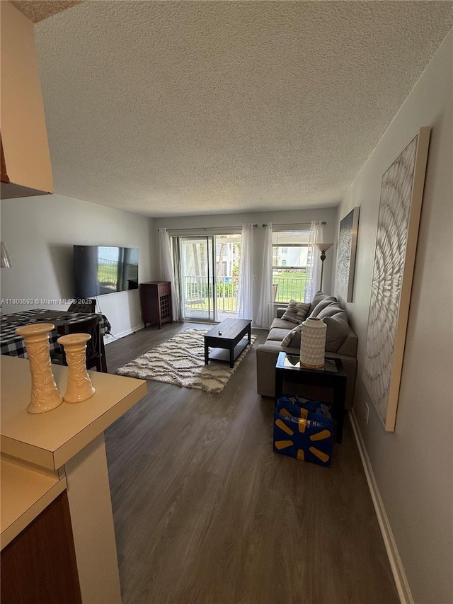 living area featuring a textured ceiling, dark wood finished floors, and baseboards