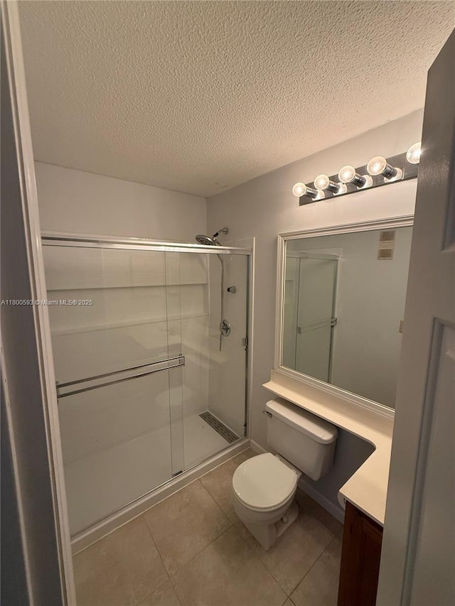 full bathroom featuring a shower stall, toilet, vanity, tile patterned floors, and a textured ceiling