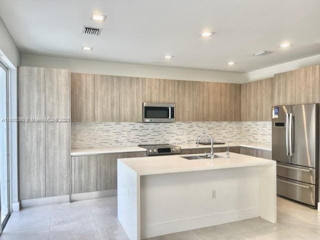 kitchen featuring appliances with stainless steel finishes, modern cabinets, a sink, light countertops, and recessed lighting