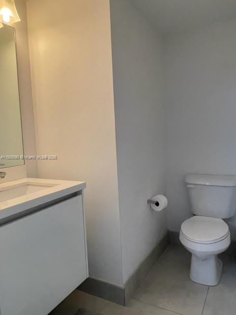 half bath with vanity, toilet, tile patterned floors, and baseboards