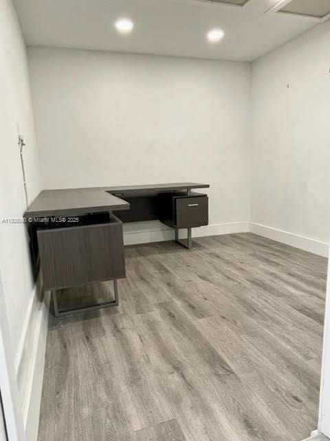 unfurnished office with wood finished floors, recessed lighting, and baseboards