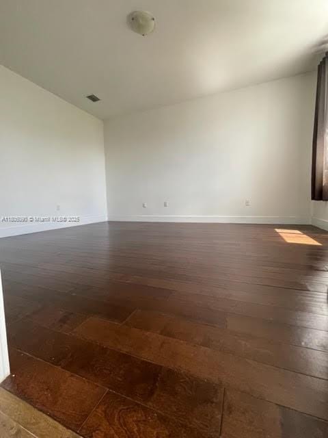 spare room with dark wood finished floors and baseboards
