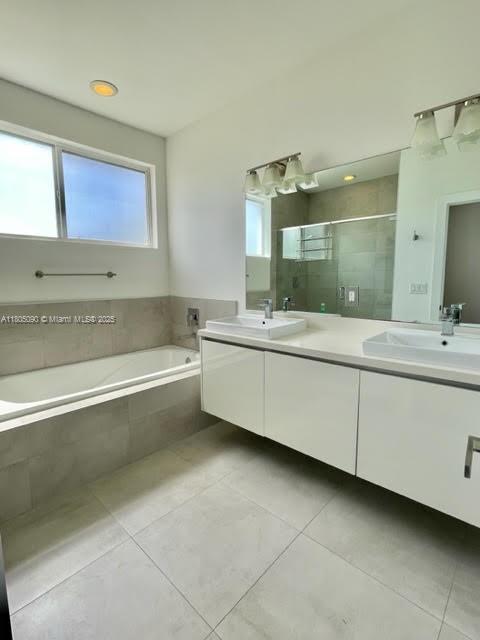 bathroom featuring tile patterned floors, a shower stall, a garden tub, and double vanity