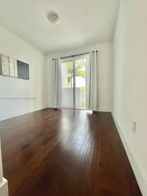 spare room with hardwood / wood-style floors and baseboards