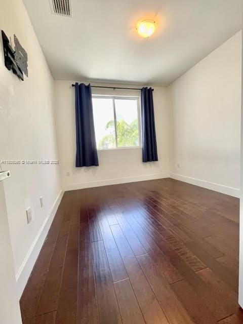 spare room featuring hardwood / wood-style flooring and baseboards