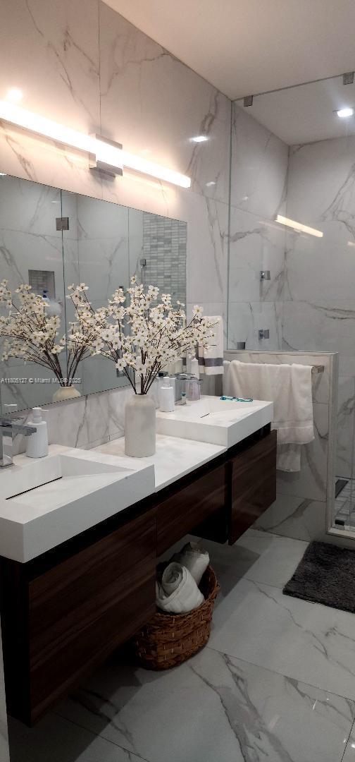 155 W 60th St, Hialeah, FL 33012 - full bath featuring vanity, tile walls, marble finish floors, a marble finish shower, and stone wall