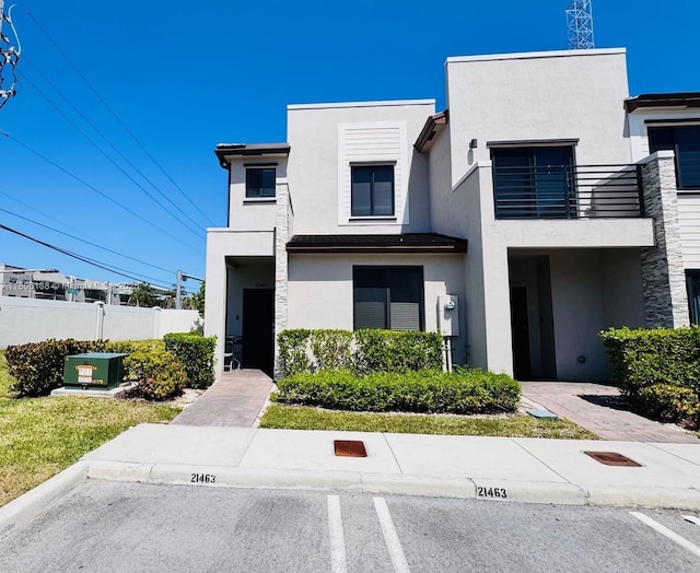 21463 NE 3rd Path, Miami, FL 33179 - modern home with stucco siding, a balcony, fence, and uncovered parking