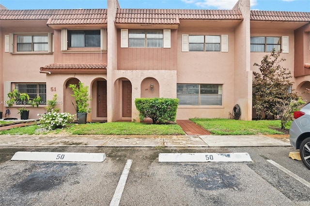 50 Matador Ln Unit 3-23, Davie, FL 33324 - view of property featuring a tiled roof, uncovered parking, and stucco siding