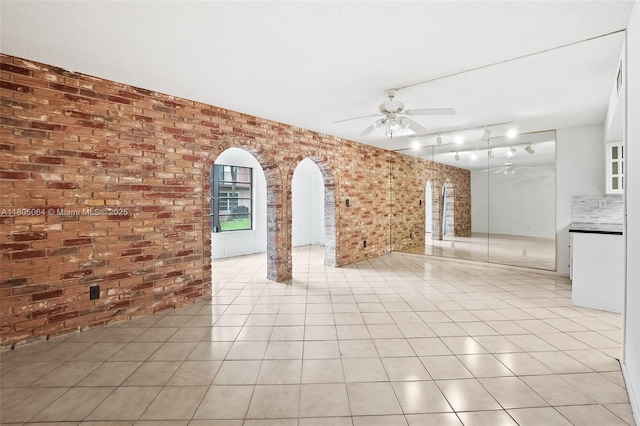 50 Matador Ln Unit 3-23, Davie, FL 33324 - unfurnished living room featuring brick wall, ceiling fan, arched walkways, and light tile patterned floors