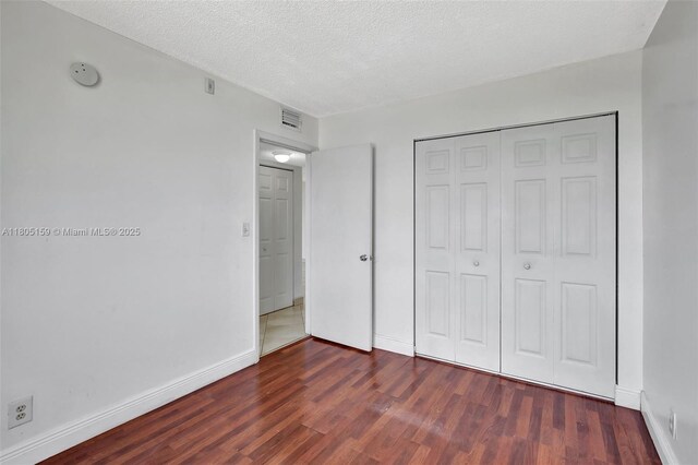8720 N Sherman Cir Unit 401, Miramar, FL 33025 - unfurnished bedroom featuring wood finished floors, a closet, and a textured ceiling