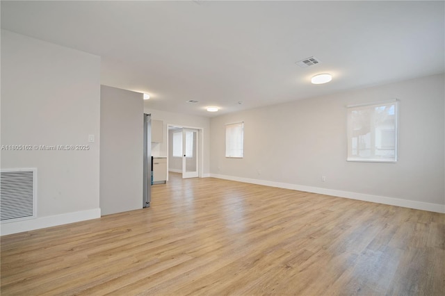 unfurnished room with plenty of natural light, light wood-style flooring, and baseboards