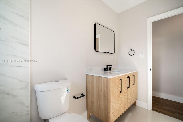 bathroom featuring toilet, vanity, and baseboards