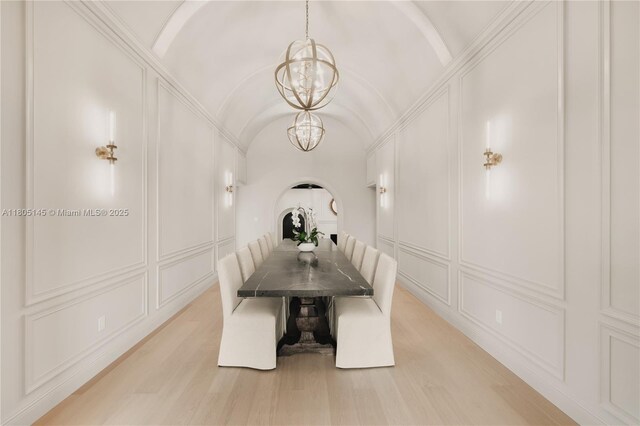 549 NE 59th St, Miami, FL 33137 - unfurnished dining area featuring a chandelier, a decorative wall, lofted ceiling, light wood-type flooring, and arched walkways