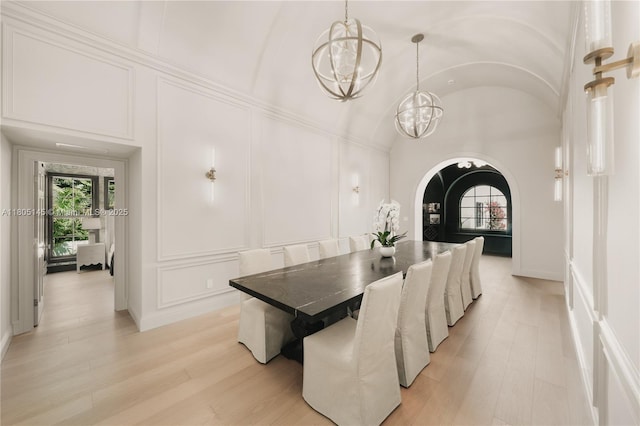 549 NE 59th St, Miami, FL 33137 - dining room with a decorative wall, a chandelier, arched walkways, light wood-style flooring, and vaulted ceiling