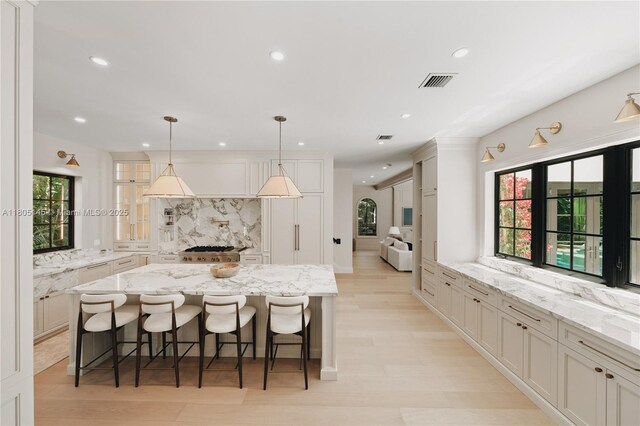 549 NE 59th St, Miami, FL 33137 - kitchen featuring a kitchen island, a kitchen bar, recessed lighting, white cabinetry, and light wood finished floors