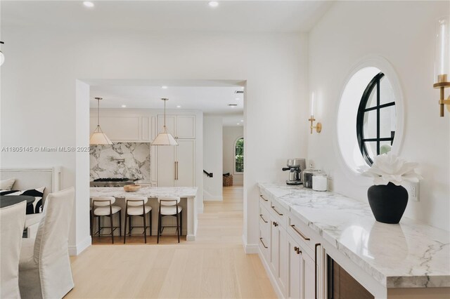 549 NE 59th St, Miami, FL 33137 - kitchen featuring a breakfast bar, decorative backsplash, recessed lighting, light stone countertops, and white cabinets