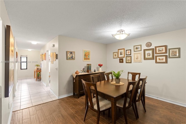 dining space featuring wood finished floors, a textured ceiling, and baseboards